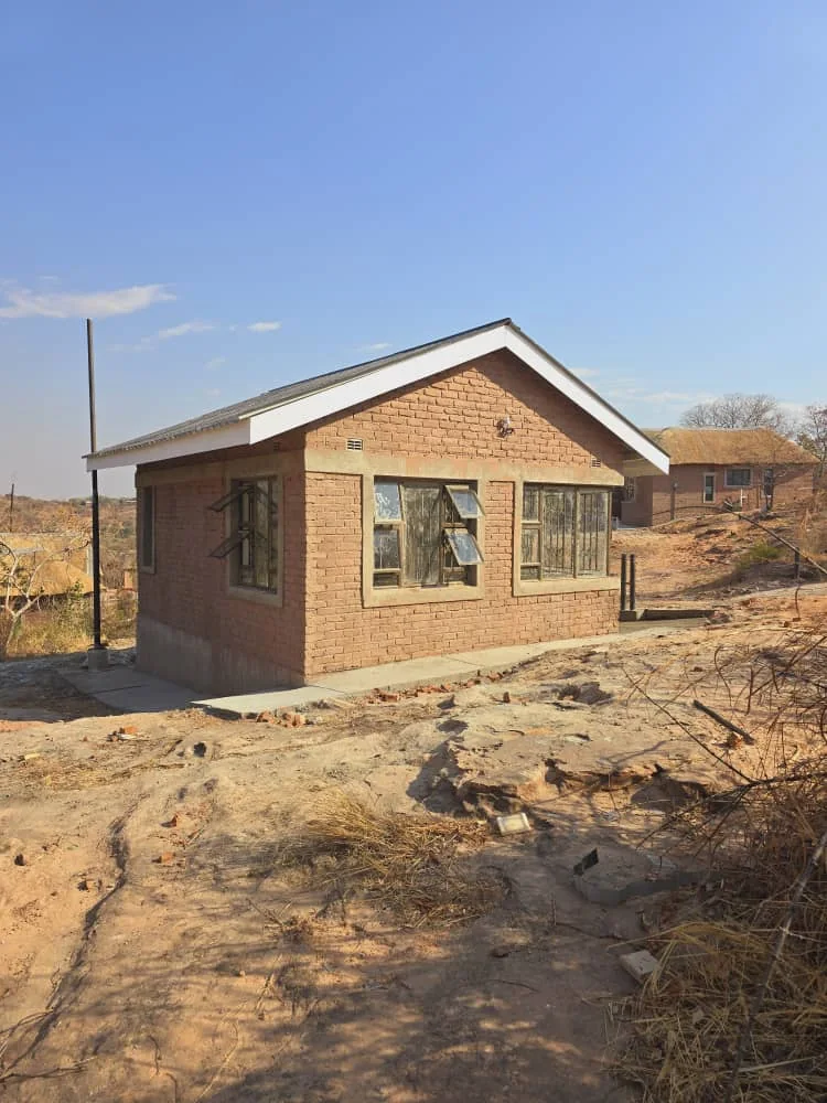 A face-brick lodge shell under its new roof at Kanyemba